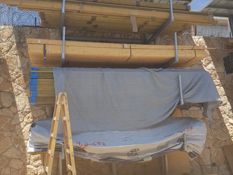 קורות עץ מסודרות על מתקן אחסון תחת גגון