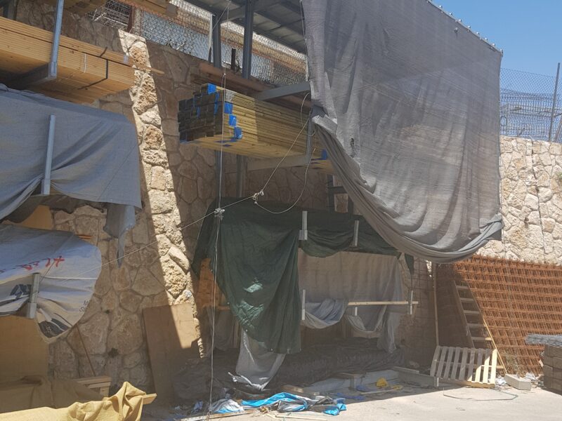 אזור אחסון מקורה לקורות עץ ורשתות ברזל בחצר