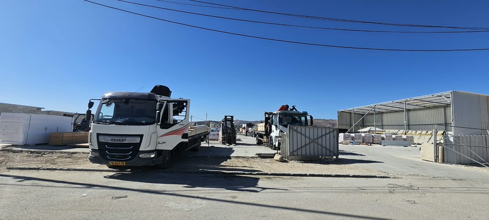 חצר הסניף עם משאיות הובלה ומחסן חומרי הבניין