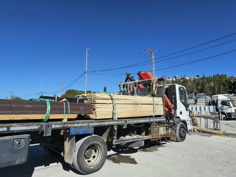 משאית מנוף עמוסה בחבילות עץ לפני יציאה למשלוח