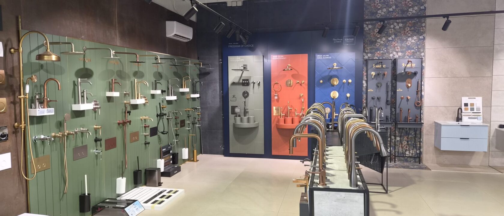 קיר תצוגה של ברזים ומקלחות על רקע ירוק, כתום וכחול